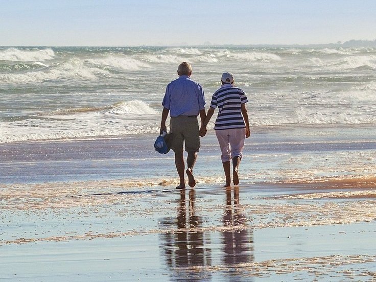 Eine Frau und ein Mann gehen an einem Strand spazieren.