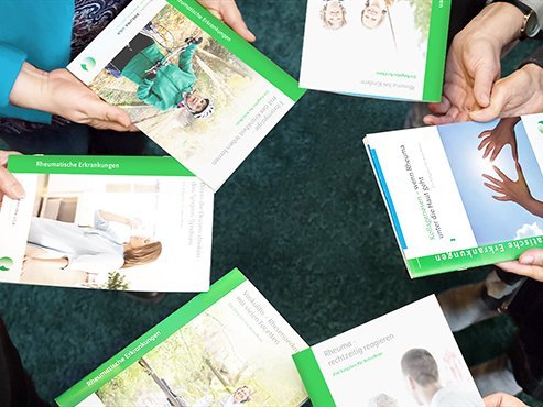 Mehrere Personen halten Rheuma-Broschüren in den Händen
